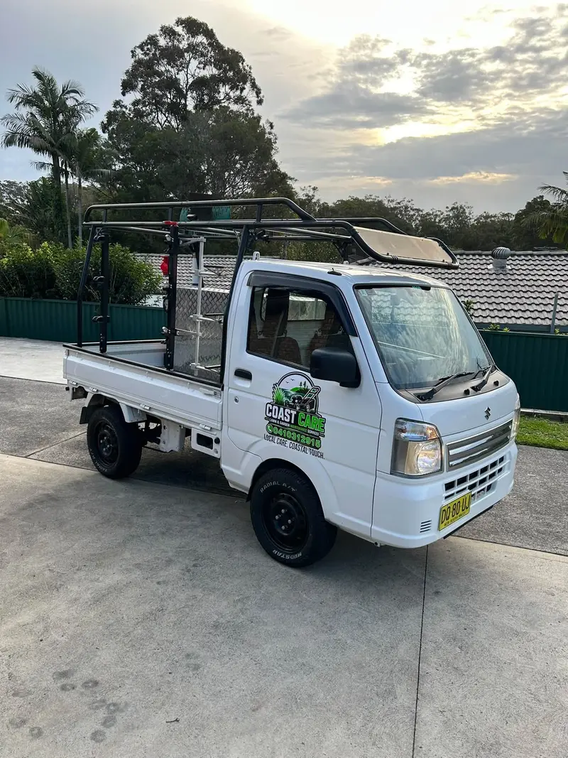 Christian's Coast Care Suzuki Carry truck with the logo on the door, parked at a Chittaway Bay home