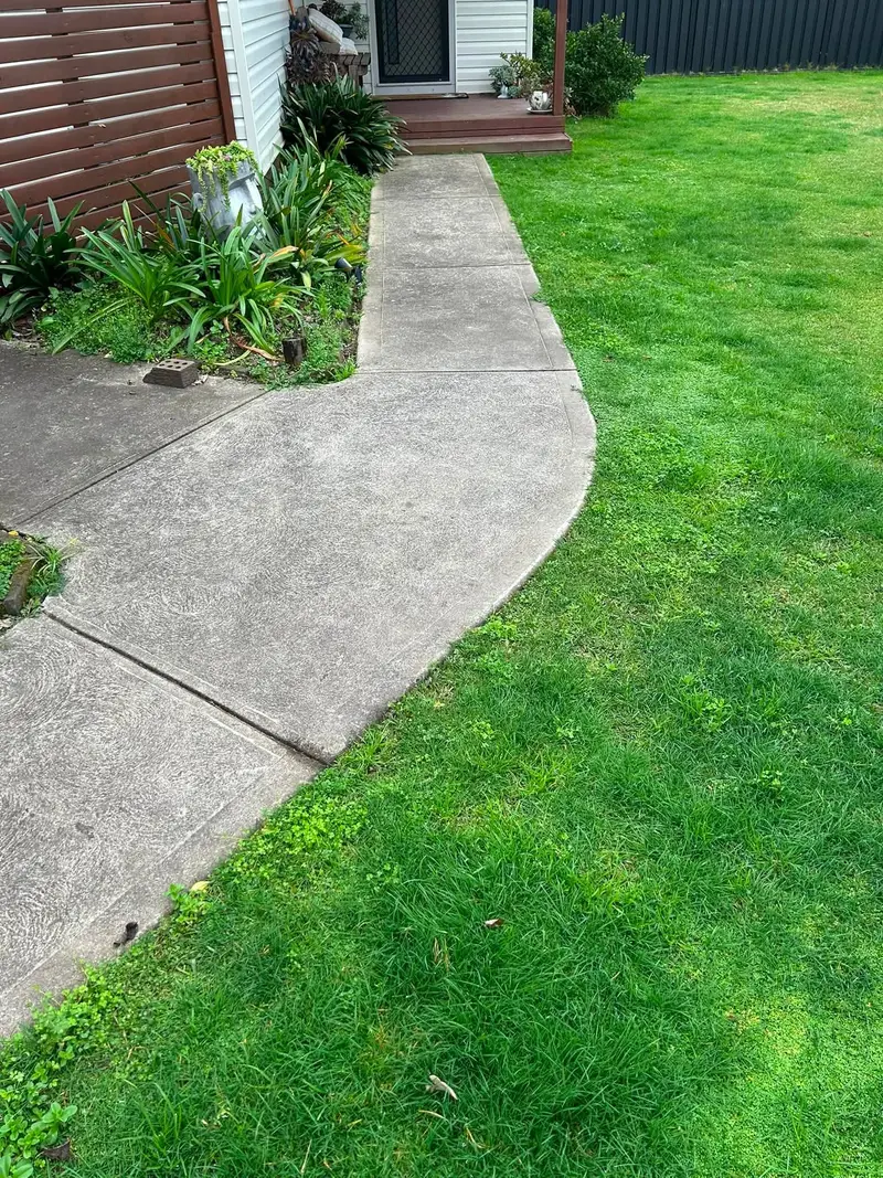 A lawn mown and edged cleanly along a concrete path