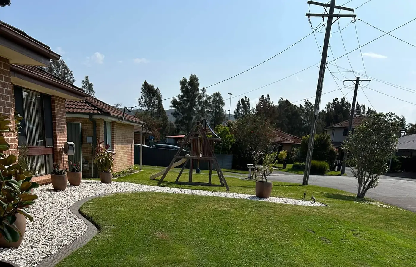 A mown lawn with clean edges against a white pebble border and driveway